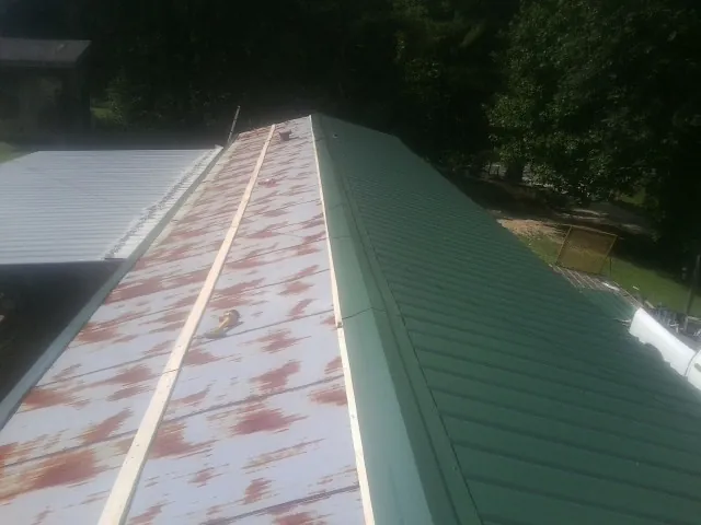 Old rusted panels beside newly installed green metal roofing — Wind Damage Roof Repair by Roofing Brothers in Crestwood