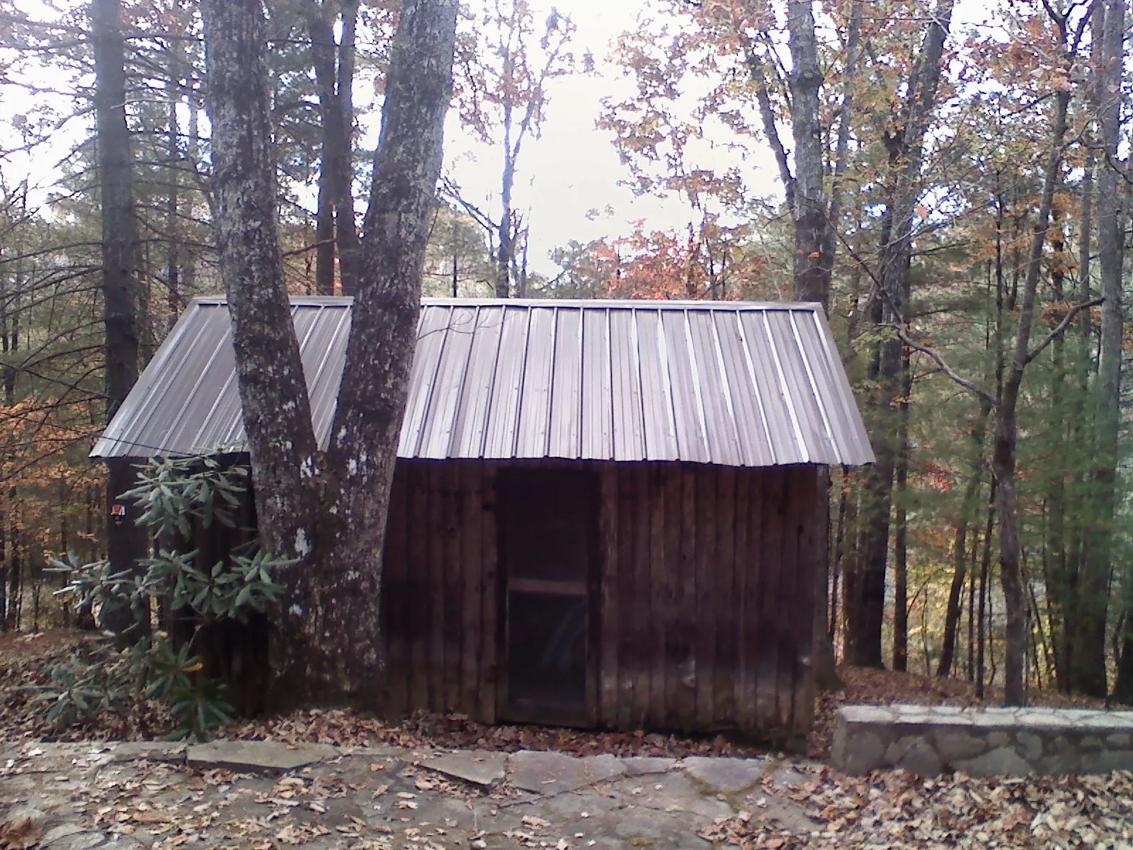New metal gable roof on a small log shed among the trees in Crestwood