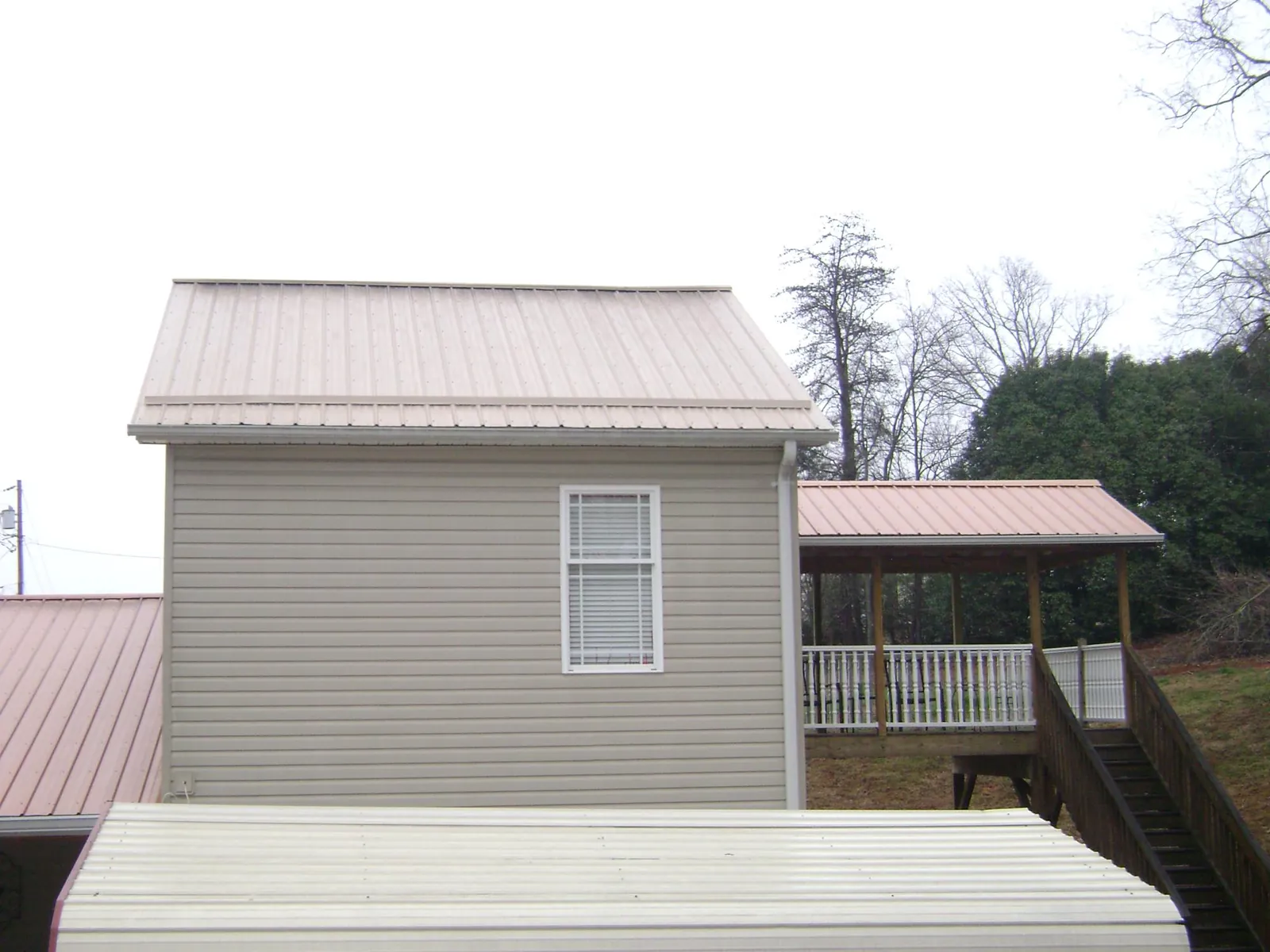 Tan metal roofs on a two story addition and attached porch, from a Roof Replacement job in Crestwood